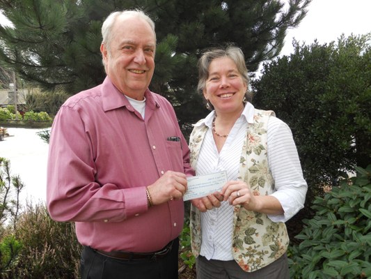 Doug Bechtel presents a check for funds raised by Actors' Theater audiences to Hilary Canty of the Community Foundation. The funds will benefit the rebuilding of the Orcas Exchange.