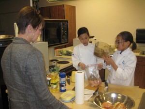 Last year's grand prize winners, Millie Kau and Sabrina Bailey show judge Susan Babcock ingredients they are preparing for their Caribbean Chicken Casserole