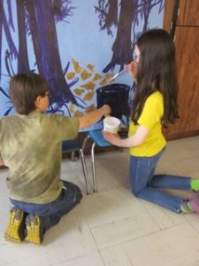 5th graders Joseph Brewer and Maya Heikkinen apply their art to a woodland mural which also includes bark from Mexico for texture and a real woodland feel, says artist Michele DeLong.