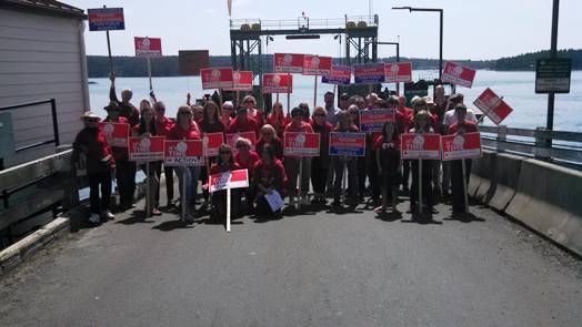 Wearing Red to show Support for Education, local public school supporters rallied at the Orcas ferry landing on Sunday, May 17