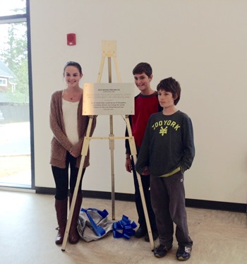 Students Jo Gudgell, Landon Carter and Evan King unveil the new plaque.