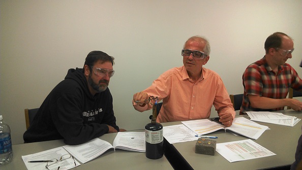 School Board directors, from left, Scott Lancaster, Tony Ghazel and Chris Sutton turn zinc-copper pennies to "gold" in a hands-on demonstration of applied physics at the school board meeting