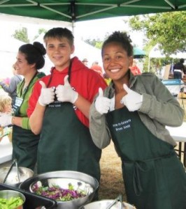Stephanie Shaw and Cameron Schuh give a big thumbs up for the fresh organic salads made at last year’s farm-to-cafeteria booth at the Library Fair. 