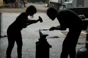 Paelle learns blacksmithing basics from Jorgen Arle as part of the FEAST program