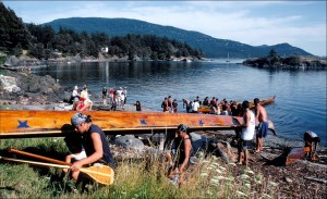 Peter Fisher photo of the Lummi Canoes' visit in 2003. Madrona Point, tribal burial ground, is in the background.