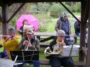 Community Band members Moana Kutsche, Sandra Durand (under pink umbrella) Pat Muffet, Ken Speck and Ron Myers greet the return of the Olga Dock