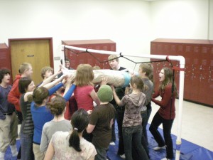 Seventh-graders pass one of their own through a web of netting in the Middle School Commons