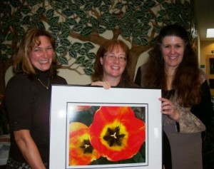 Pat Ayers and Marta Nielson flank Janet Brownell, who accepts a Michael Mele photograph on behalf of the Orcas Island School District.