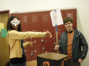 Seventh grader Diansa Anuenue (new to Orcas Island this year from Hawaii) and Chris Babcock demonstrate Babcock's numbers-theory game of chance where a random, blindfolded drop into a blue cup doubles the player's money, while a drop into a red cup ends the game.